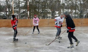Four skaters playing hockey on the Manor Park outdoor rink.