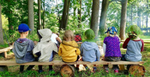 Children with their backs to us sitting on a bench.