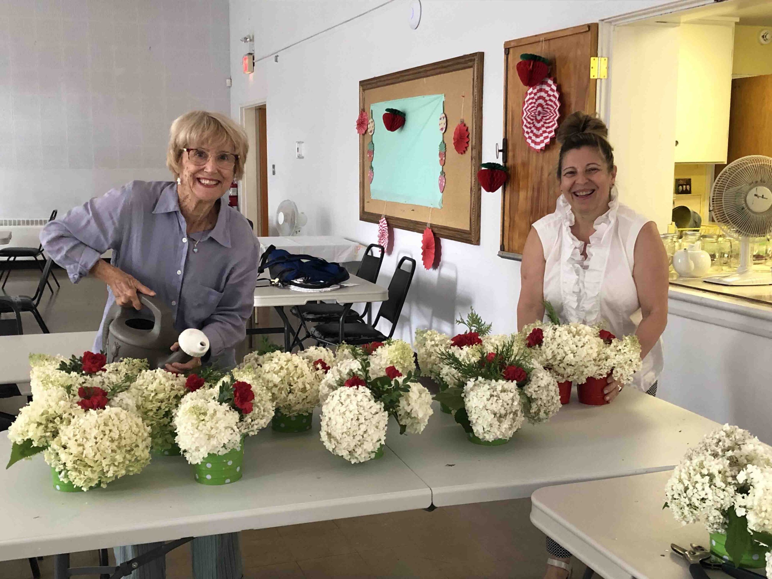 Wendy Trethewey, left, and Binda Morim preparing flower arrangements for Strawberry Social during a busy summer at St. Columba Church.